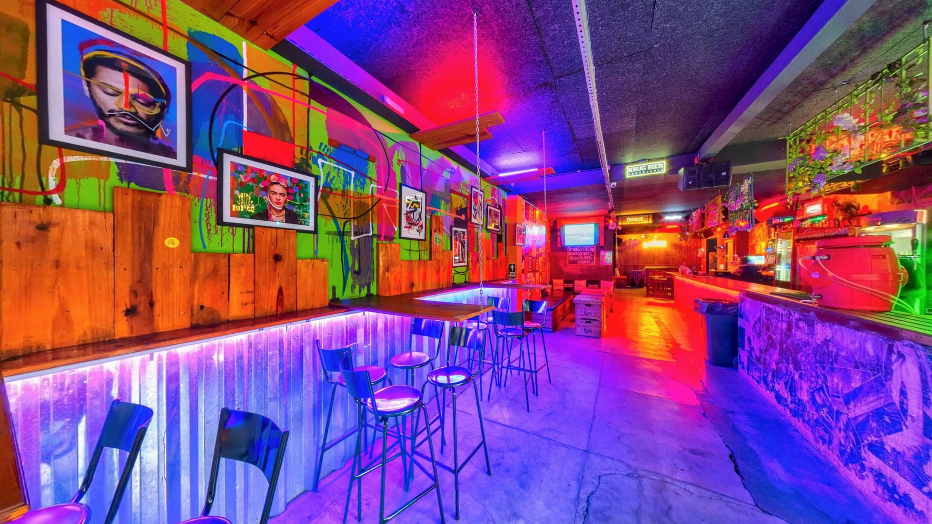 Interior da Laicos Bar Savassi com iluminação colorida, mesas e balcão